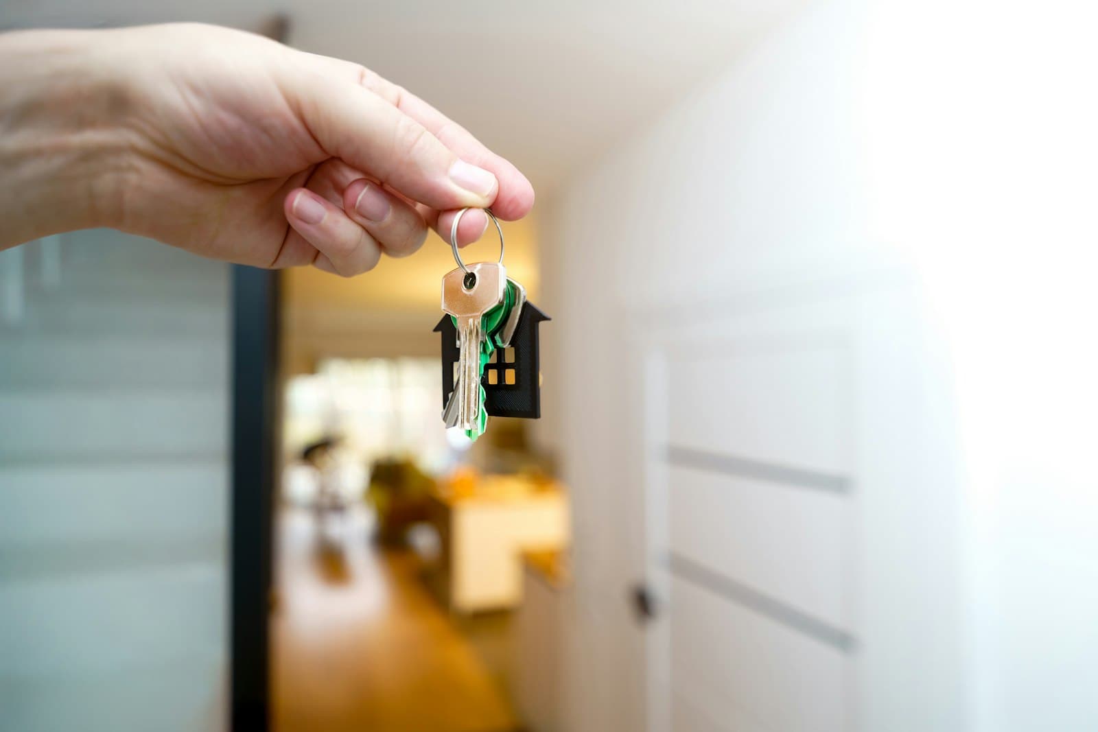 A hand holding house keys at the entrance of a home