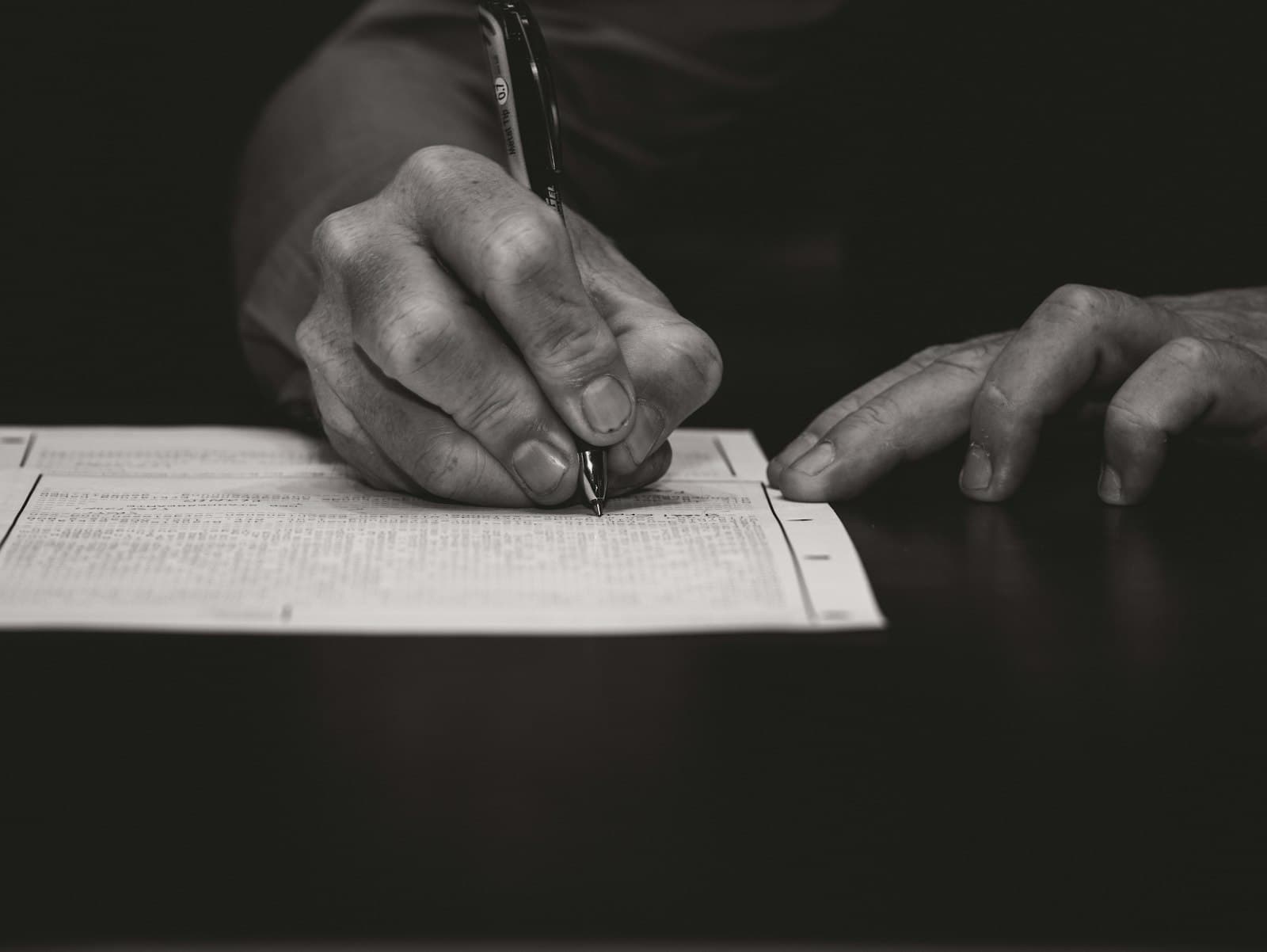 A hand signing a document with a fountain pen
